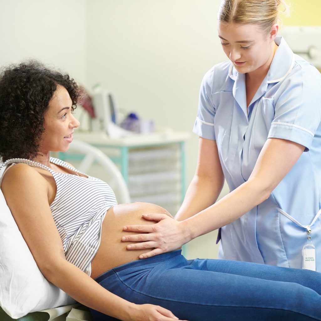 Physician putting her hands on a pregant woman's belly