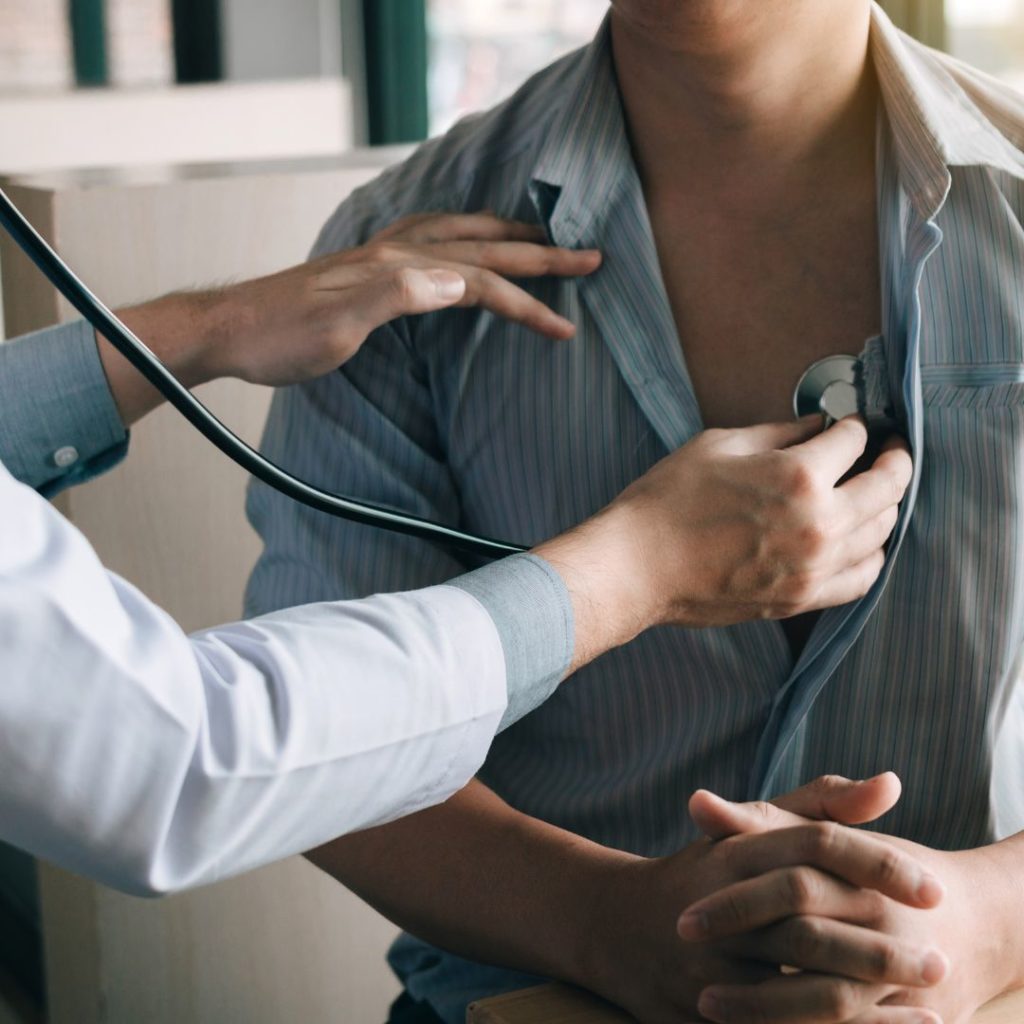 Physician holding a stethoscope up to the chest of a patient