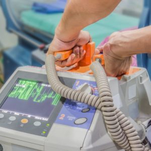 A physician grabbing defibrillator paddles